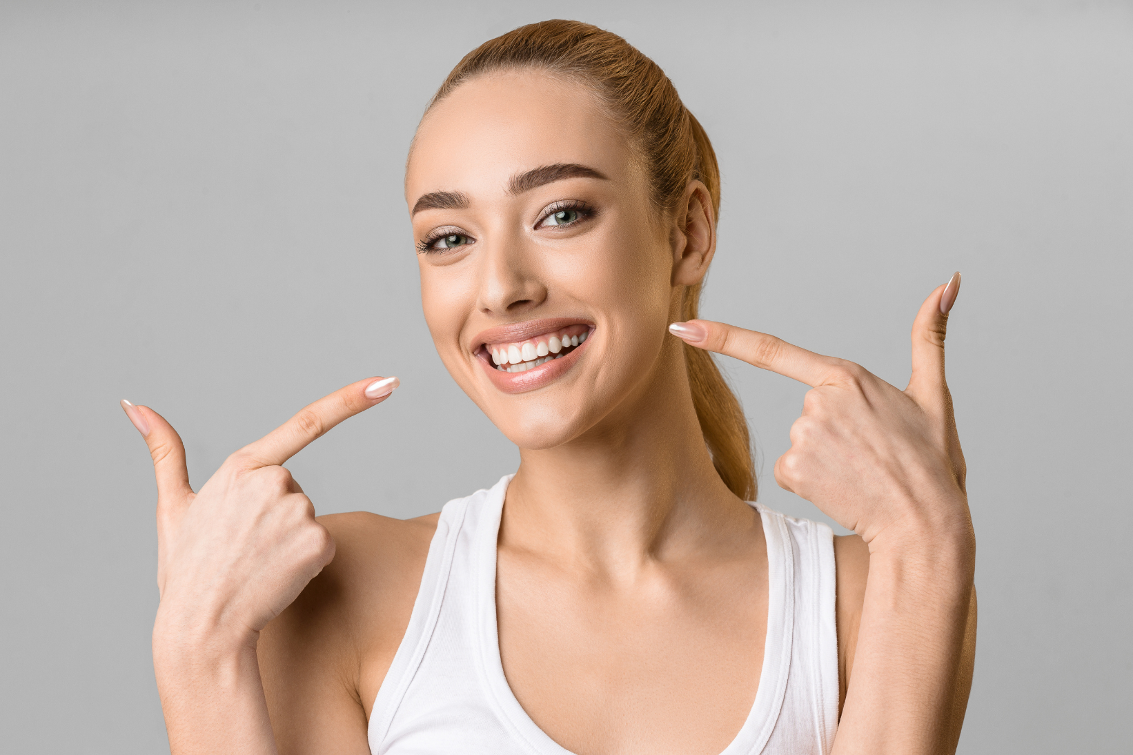Woman pointing to her beautiful smile — veneers and bonding at Christian Family Dentistry Decatur TX